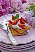 Waffles with strawberries, cream and mint leaves
