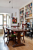 Antique chairs around wooden table in front of bookcase
