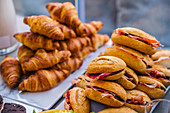 Tasty sandwiches with slices of bacon and sweet croissants served on plates for home party
