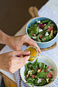 Holding jar glass with sauce for vegetarian salad made of sorrel leaves and fresh watermelon and pitaya slices