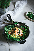 Zucchini noodles with boiled prawns and fresh spinach leaves placed on frying pan