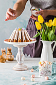 An Easter carrot Bundt cake being decorated with Easter eggs