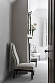 Upholstered chair with roses in vase on shelf with mirror