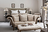 Cream two seater sofa at foot of double bed with lamps at bedside