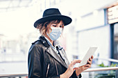 Woman in face mask using digital tablet