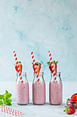 Yummy milkshake with fresh ripe strawberry on table in pink light