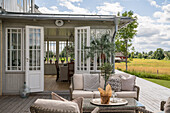 View from terrace with rattan furniture into the conservatory
