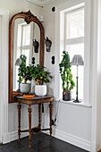 Spindly table, potted orange tree and antique wall mirror in corner of room