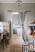 Desk, chair and doll's house in girls' bedroom with doorway leading into kitchen