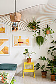Designerleuchte, viele Grünpflanzen und moderne Kunst an der Wand im Wohnzimmer