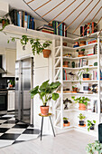 Regale mit Zimmerpflanzen und Büchern neben und über dem Durchgang zur Küche