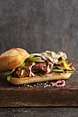 A steak sandwich with Provolone, peppers and red onions