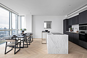 A dining room and modern kitchen with an island in a high-rise building