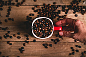 Hand greift nach Tasse mit Kaffeebohnen