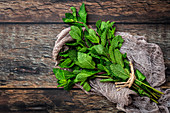 Bunch of fresh green aromatic mint twigs arranged on rustic wooden table