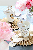 Swan clips on paper cups on paper rosettes for party table