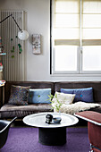 Coffee table and grey sofa with scatter cushions below window in living room