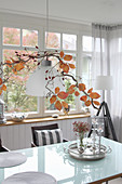Rose hips and branch with leaves above the dining table as autumn decorations