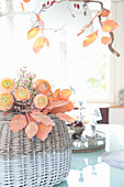 Strauß aus apricotfarbenen Ranunkeln mit Statice auf künstlichem Herbstlaub