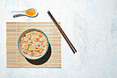 Chopsticks and bowl with freshly cooked rice with prawns and vegetables