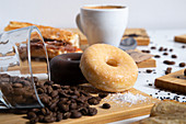 Still-life breakfast table with assorted doughnuts, coffee beans and cup