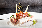 Exquisite restaurant dish of bone marrow with serving of steak tartare and crisps