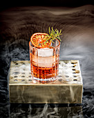 Alkoholischer Cocktail mit Blutorange, Eiswürfeln und Rosmarin
