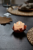 Lit candle in DIY candle holder made from autumn leaf