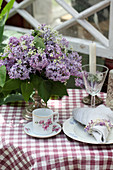 Vase of lilac and cow parsley decorating table and napkin ring made from lilac florets