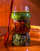 Three glasses with pickled vegetables and pesto