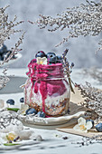 Glass jar with nutritious yogurt with healthy granola and fresh blueberries