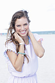 A young brunette woman by the sea wearing a light summer dress