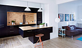 Contemporary kitchen with black cupboard fronts and free-standing counter