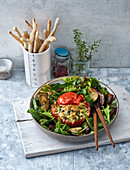 Stuffed roasted tomatoes on a mixed leaf salad with artichoke hearts