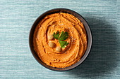 Pumpkin hummus in bowl on blue background