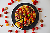 Homemade quiche with colorful tomatoes garnished with herbs and walnuts