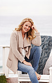 Blonde Frau in beigefarbener Strickjacke und Jeans