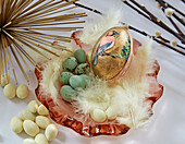 Easter egg with bird motif, sugar eggs and feathers in glass bowl