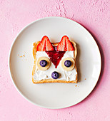 A fruit fox made from a slice of toast spread with cream cheese