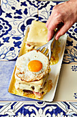 A Portuguese Francesinha (toasted sandwich with meat, cheese and a fried egg) being made