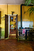 View of old wood-burning stove in rustic kitchen with yellow wall