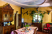 Esstisch und antike Anrichte in Wohnküche mit gelben Wänden
