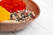 Assorted colorful spices including peppercorns, paprika and turmeric