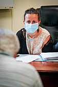 Man in consultation with a GP wearing a surgery mask