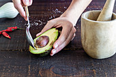 Wife with spoon taking seed from halved avocado