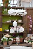 White, crocheted Easter eggs hanging from wreath of feathers