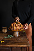Person cuts bundt cake placed on cake stand