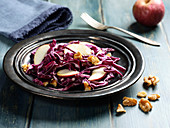 Red cabbage salad with apples wedges and piece of nuts