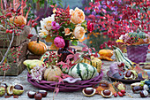 Strauß aus Rosen und Hagebutten zwischen Kürbissen, Hortensienblüte, Ranke vom wilden Wein und Kastanien als Deko