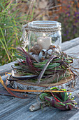 Lantern in a wreath of grasses, decorated with snail shells on a wooden disc